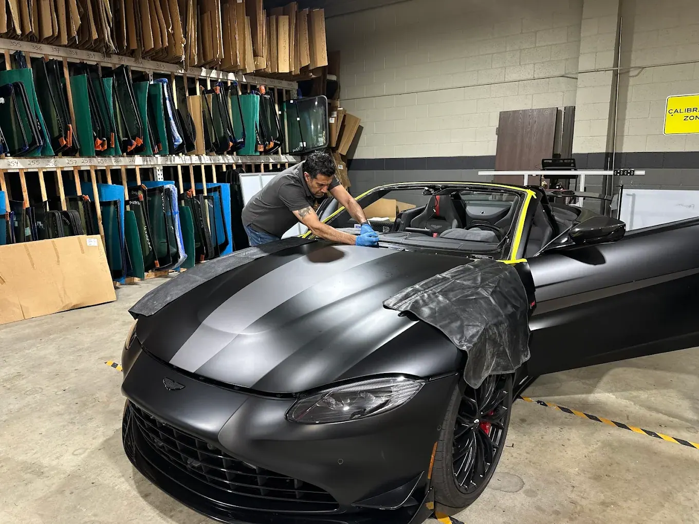 PG Auto Glass technician working at the windshield opening of an Aston Martin in the shop